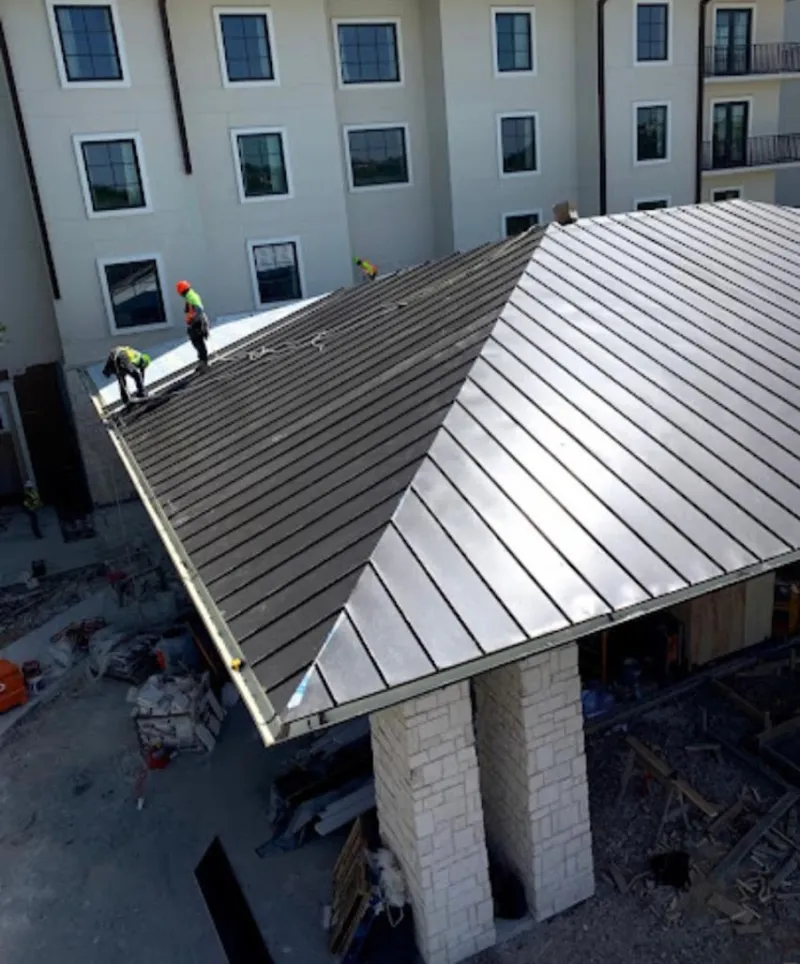 Crew installing standing seam metal roof panels on a commercial project in West Vincent